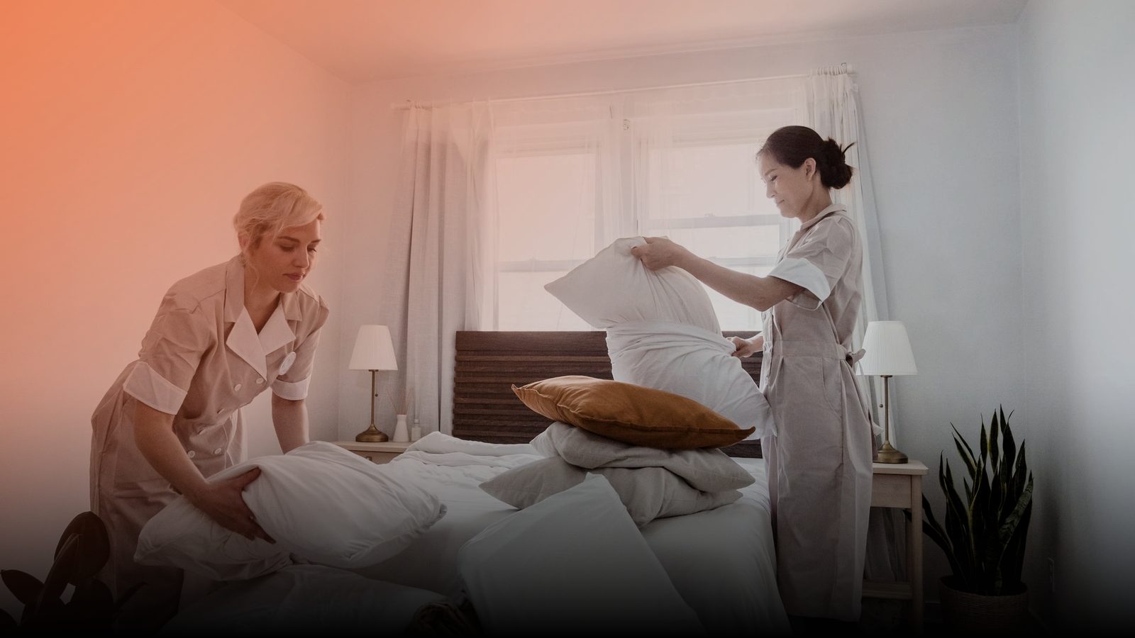 Two housekeepers making up a bed in a bright bedroom