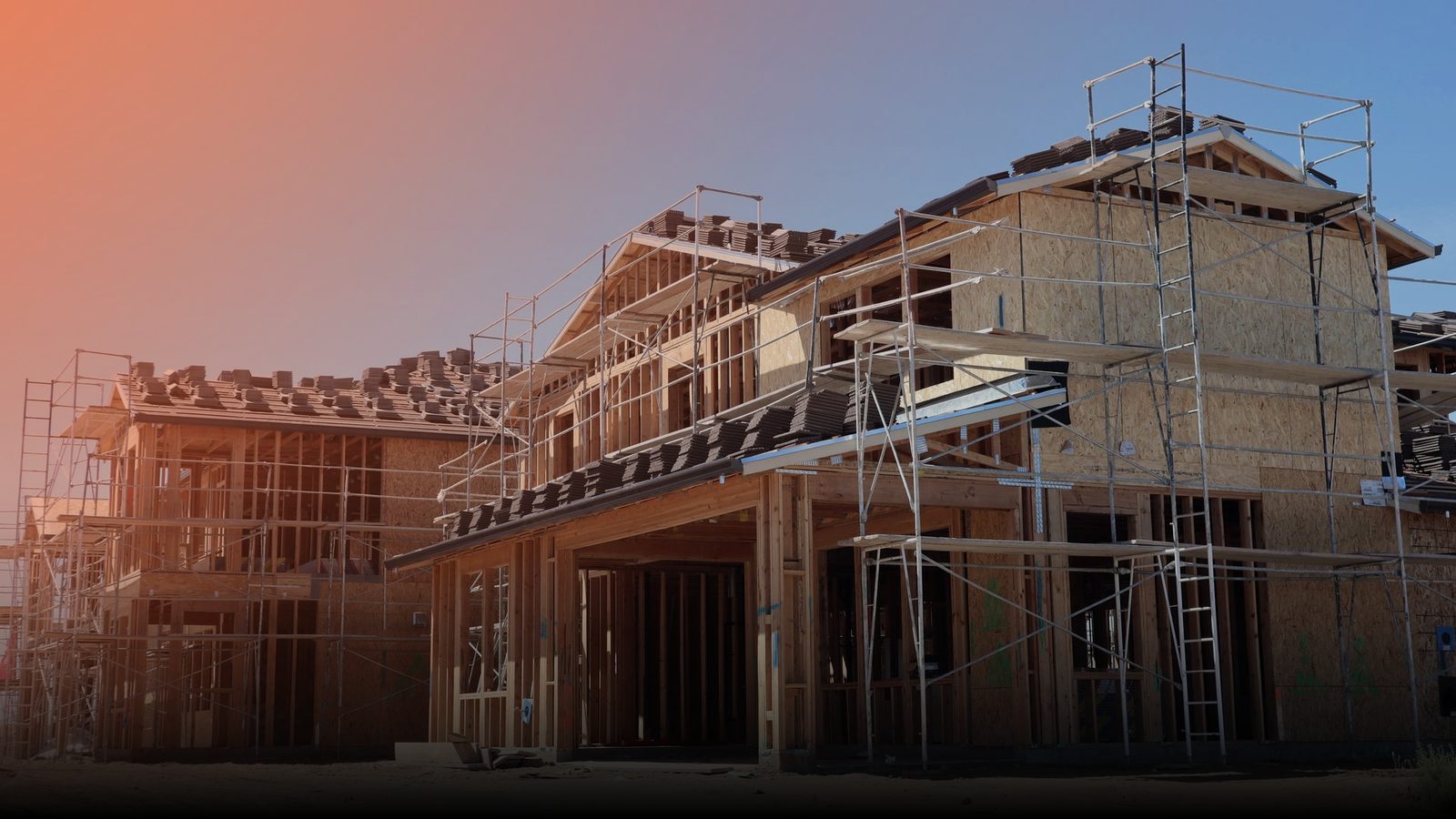 A wood-framed house under construction against a blue sky