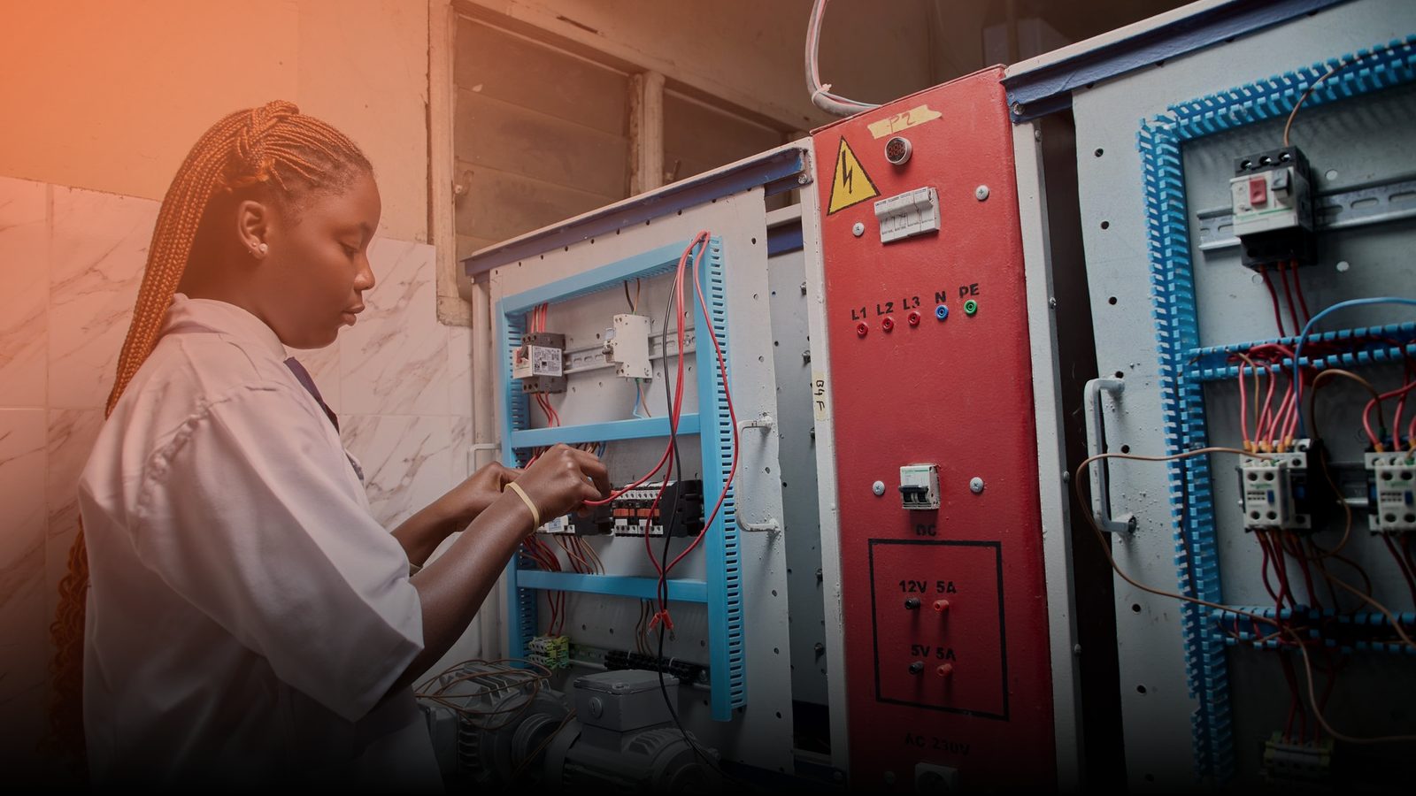 An electrician working inside an open electrical control panel