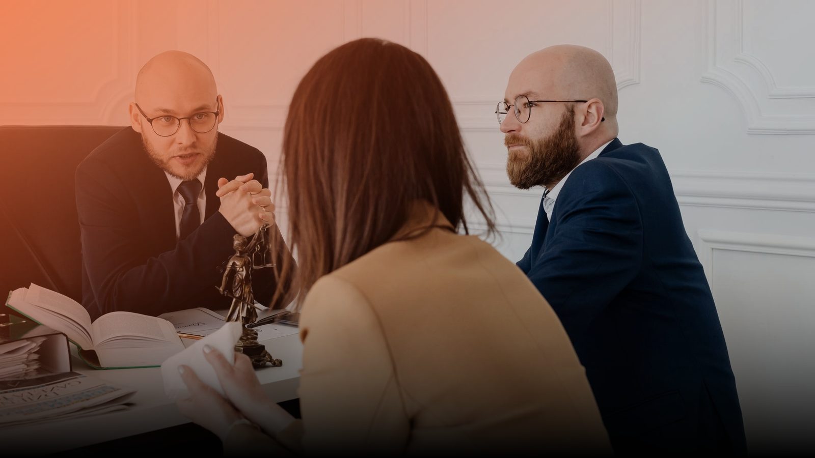 Two attorneys meeting a client across a desk