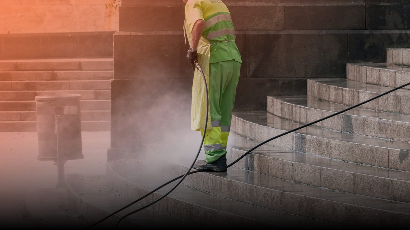 A worker pressure washing a set of stone steps